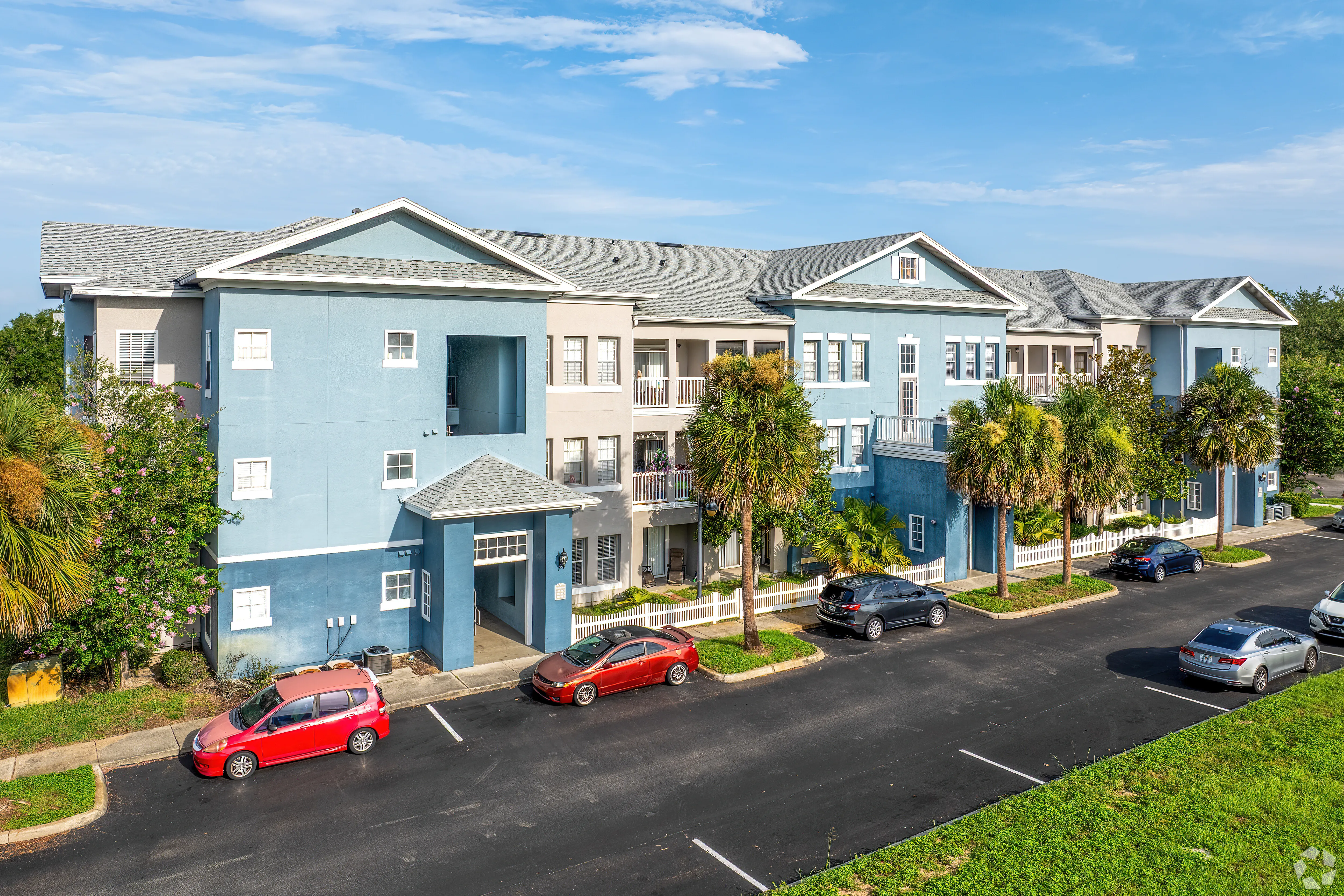 A row of apartment homes with cars parked in front.