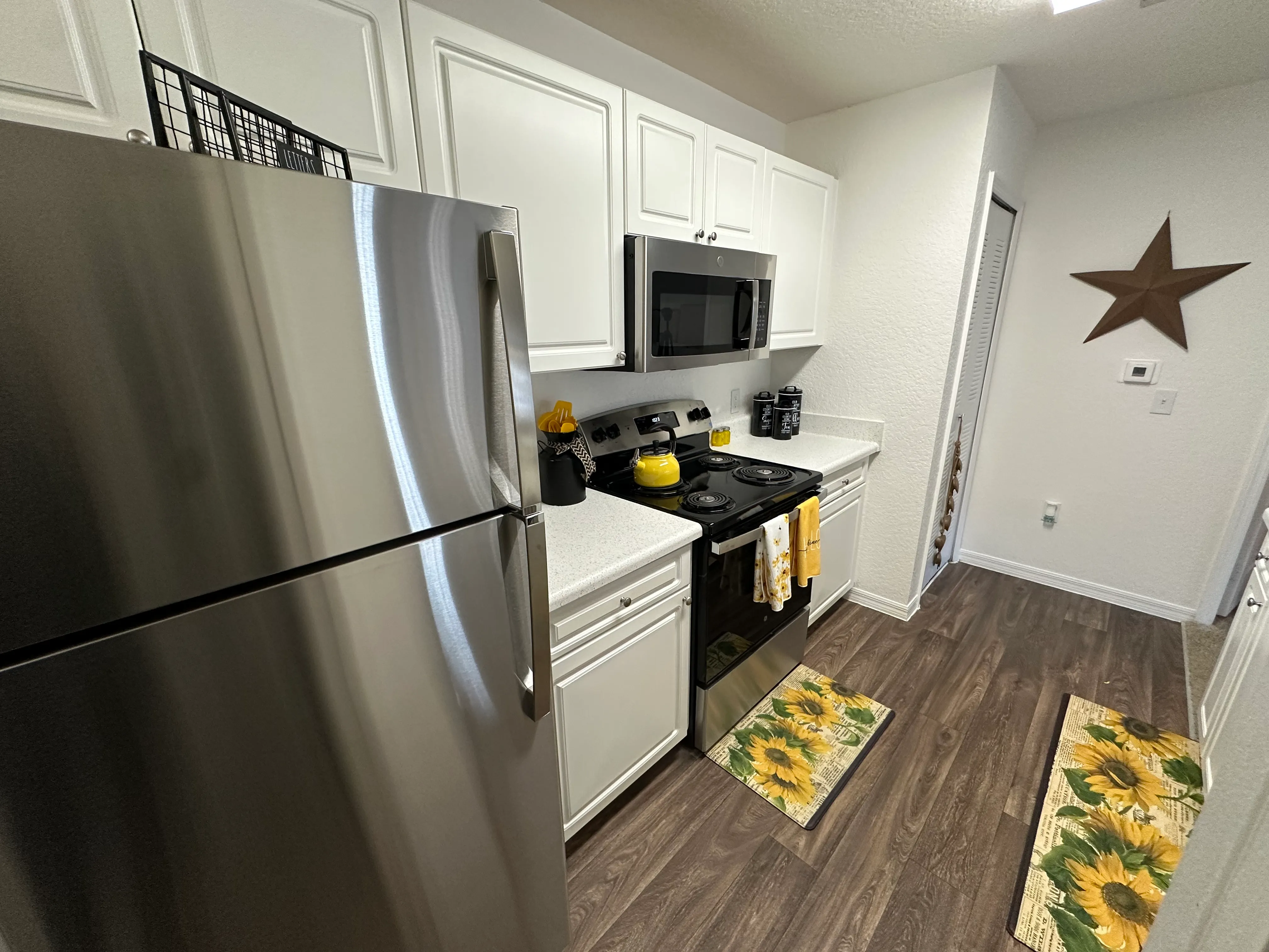 A kitchen with a stainless steel refrigerator, microwave, and a star decoration on the wall.