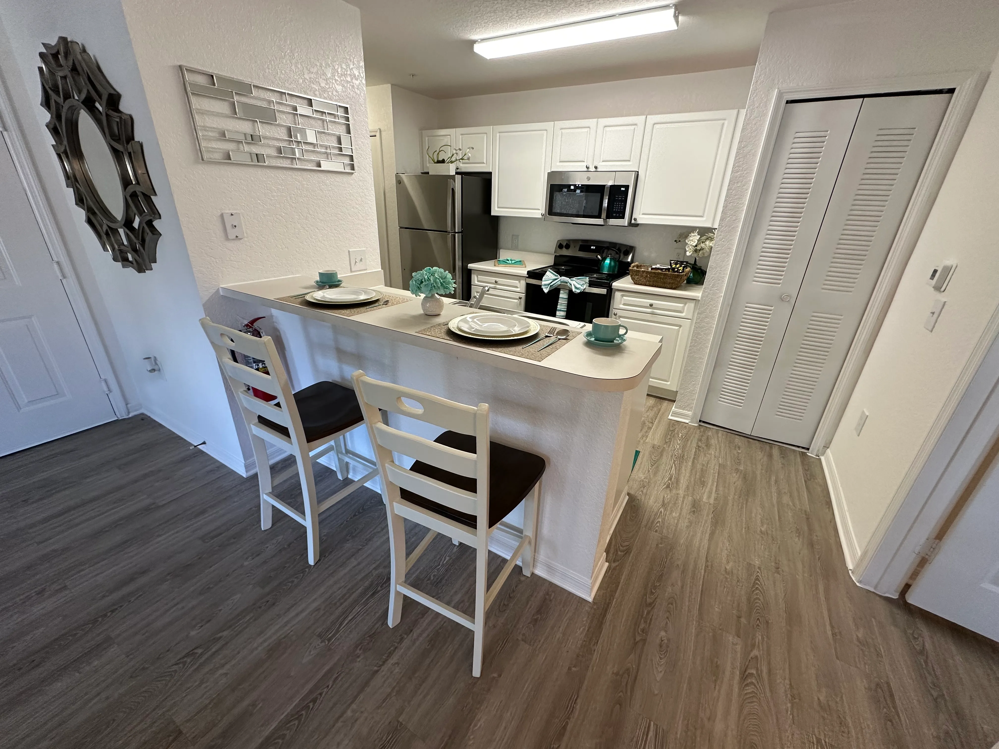 A kitchen with white cabinets and a wooden floor.