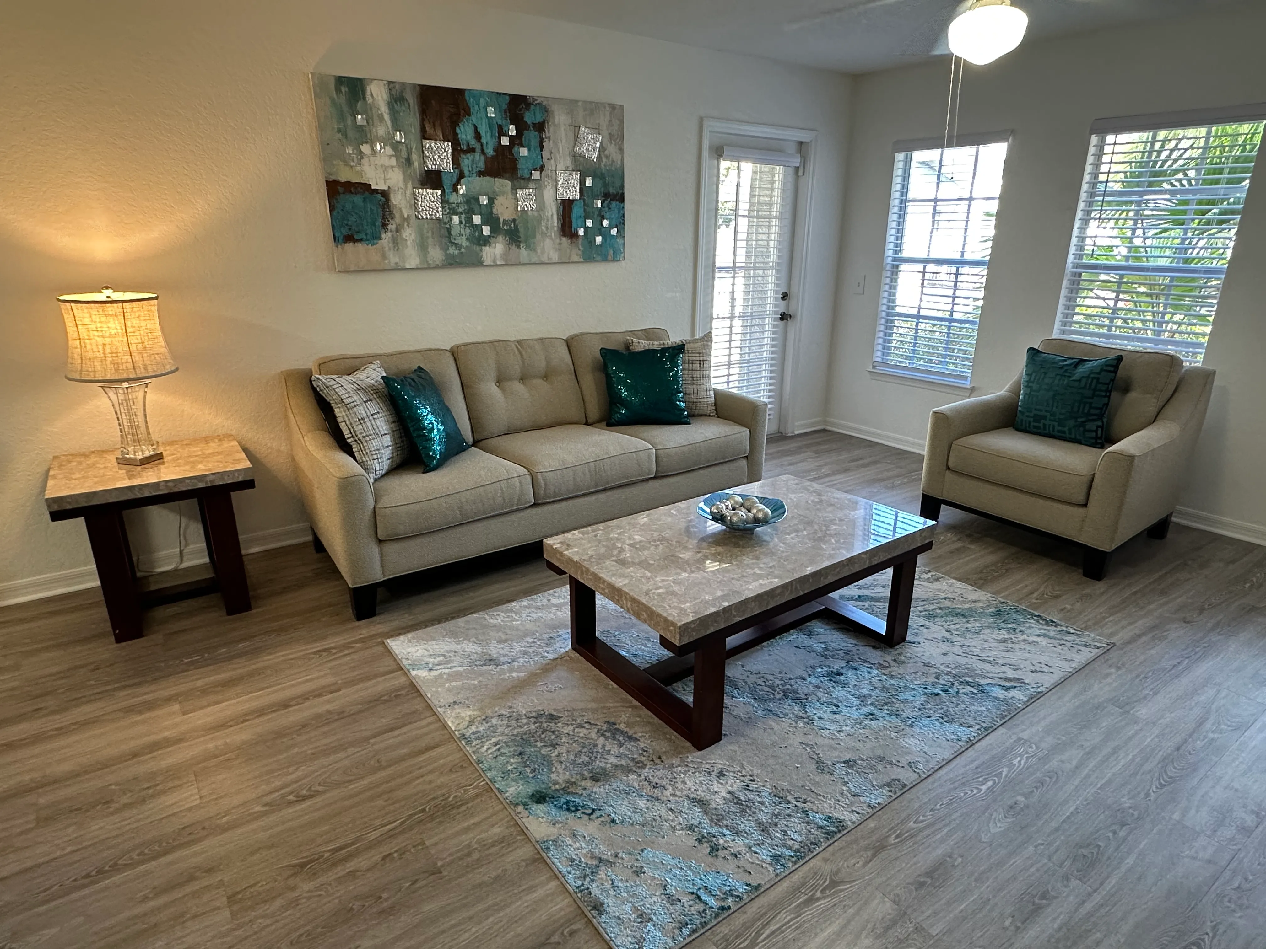 A living room with a couch, chair, and a painting on the wall.