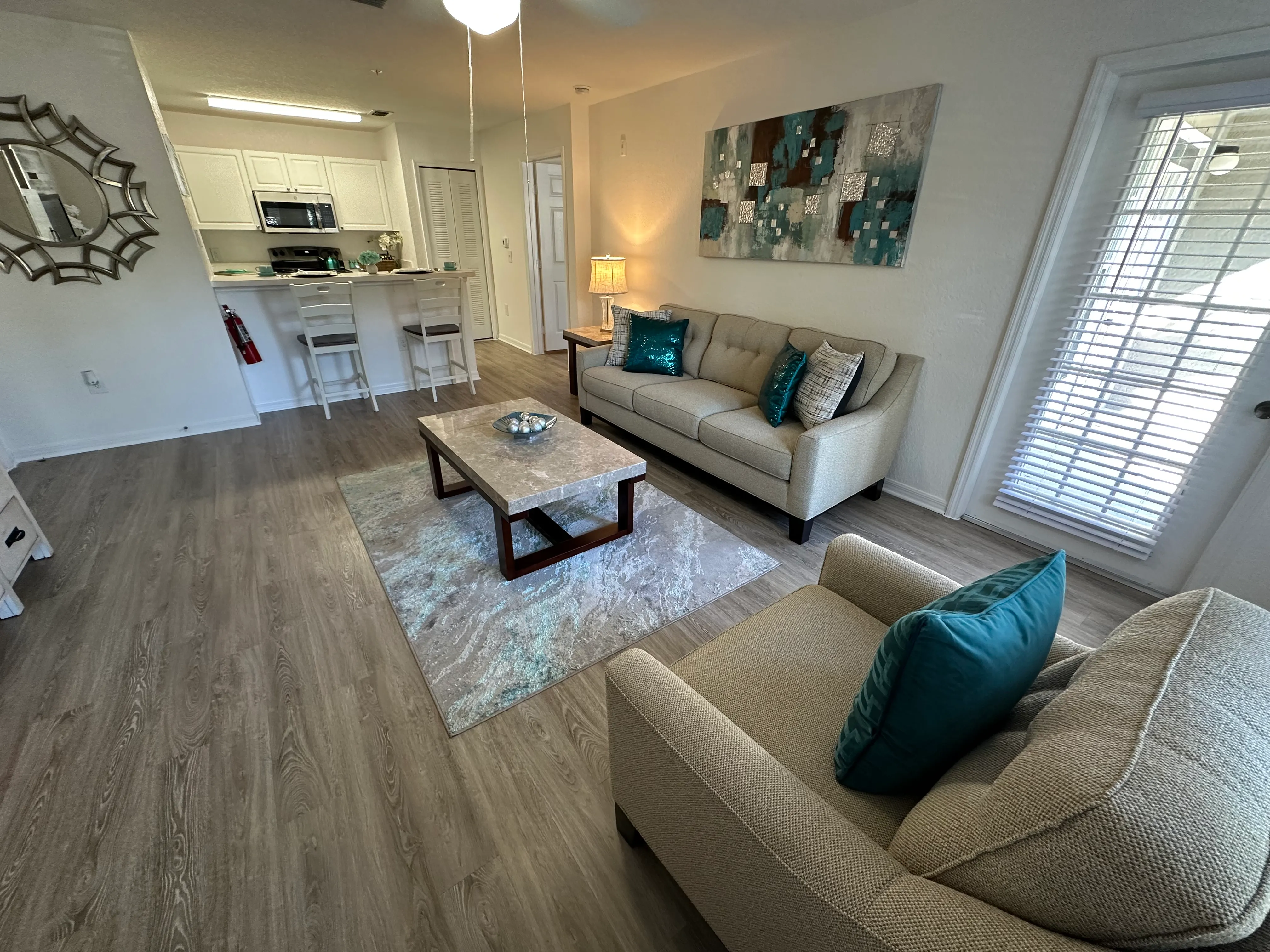 A living room with a couch, coffee table, and a painting on the wall.